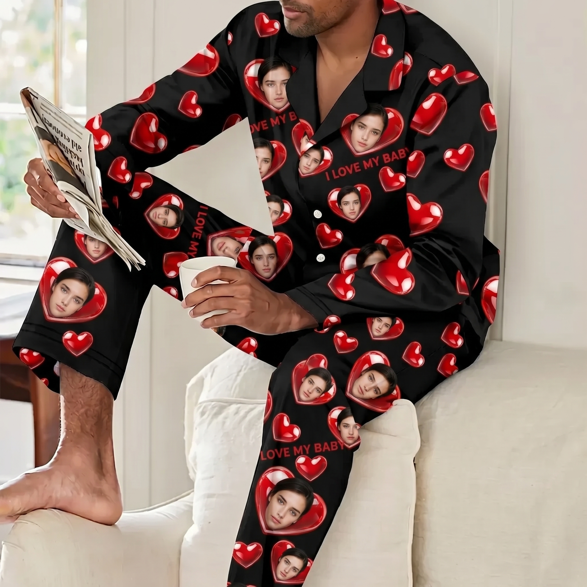 Man relaxing on a sofa wearing personalized black pajamas printed with custom face photos and red hearts