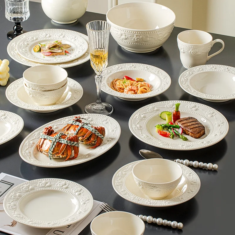 Set of bowls, plates and cutlery with embossed designs. Ceramic dinnerware set including plates, bowls and dishes.