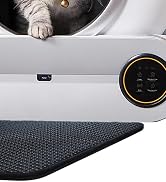 Automatic pet feeder with a digital control panel. The white device features a circular opening through which a cat's paw is visible. A dark, textured mat under the feeder.