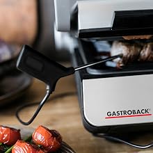 Tekst brzmi „GASTROBACK”. Profesjonalna konfiguracja urządzenia kuchennego ze sprzętem ze stali nierdzewnej i czerwonymi składnikami widocznymi w tle.